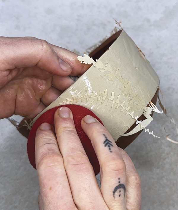 8 Place a newsprint stencil on the slip and stick with water and damp sponge.