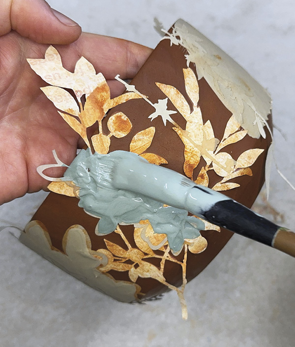 9 Place negative-space stencils, and cover with two coats of colored slip.