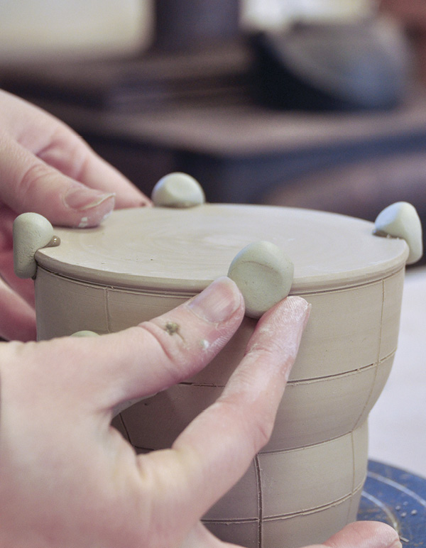 4 Attach and shape colored-clay feet in four spots on bottom of the cup.