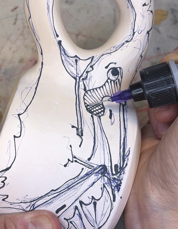 13 Using a squeeze bottle, trace all the pen lines with black underglaze.