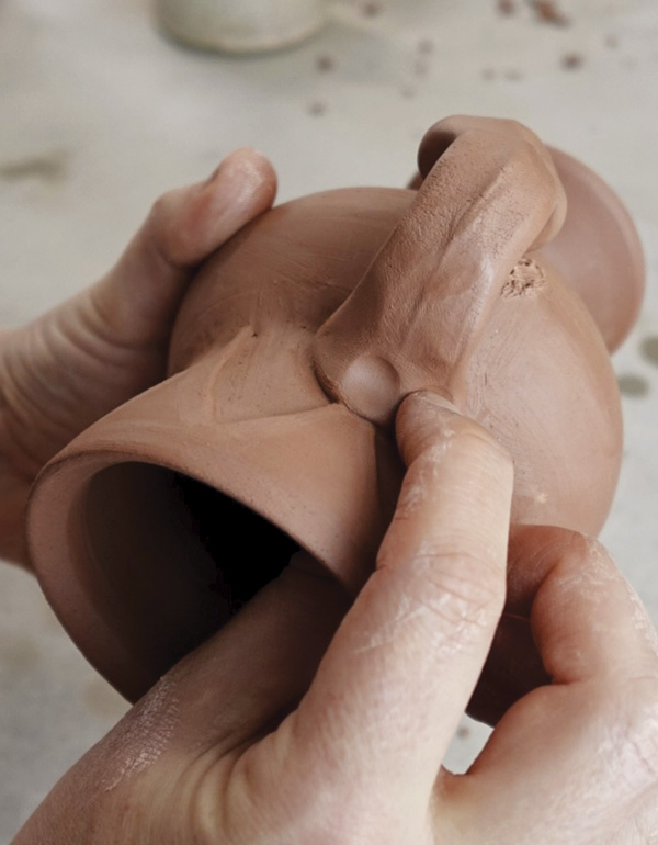 8 Pinch clay into a bone shape, then attach it to the mug body.