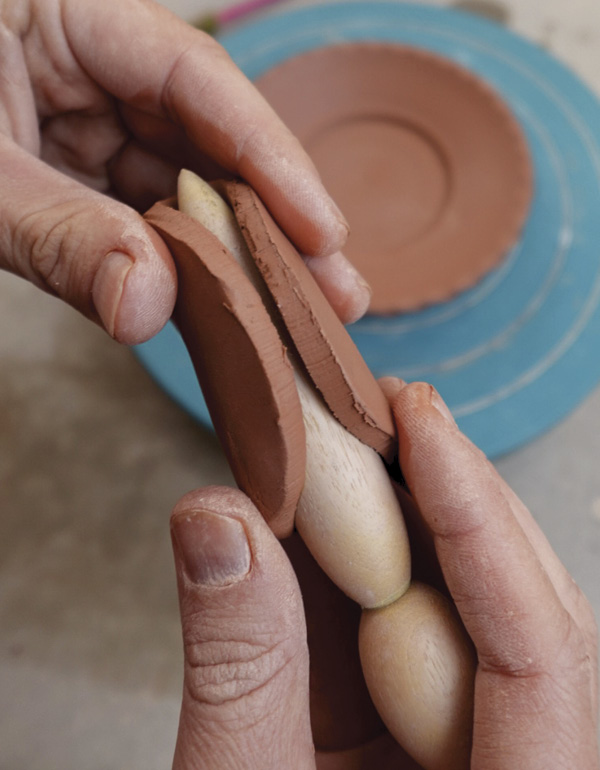 12 Gently fold a slab of clay around a wooden tool to create a hollow form.
