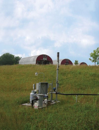 At EnergyXchange, in Burnsville, North Carolina, methane gas from a former landfill is collected by an underground system of vents and fed to the above ground distribution valve (foreground). The gas is then used to fire ceramic kilns and gas furnaces and to heat studios (background).