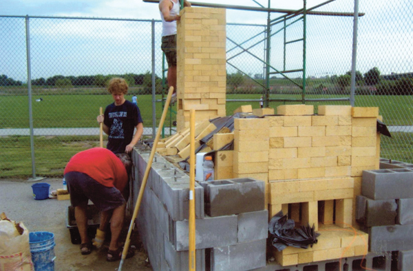 A concrete block wall helps bear some of the weight of the roof and is placed 4 inches from the sides. The gap is later filled with pea gravel.