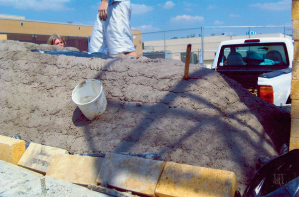 Plastic buckets were used as forms to create side stoke holes in the roof. A fiber blanket was added then the roof topped with an adobe mix of concrete, mud and straw.