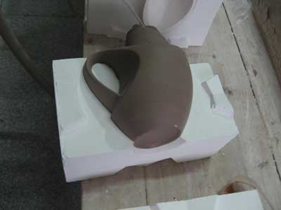 After slip casting, the cup is allowed to dry somewhat before trimming off the sprue and removing mold seams.
