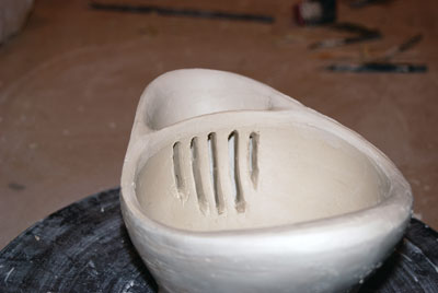 7. Perforations cut into the wall of the bowl leading into the spout.