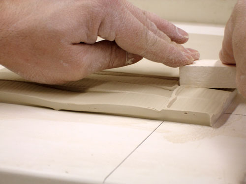 Fig.7 While the clay is still on the plaster slab, use a piece of textured plaster to landscape the piece.