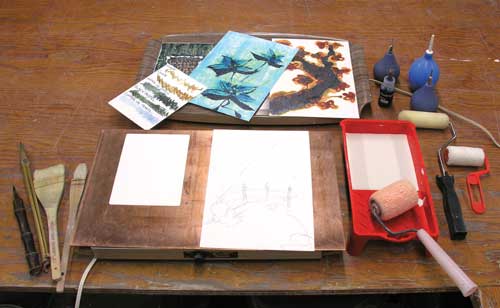 Basic working set-up with warming trays, blank and fired substrates, lambswool paint roller and glaze tray, brushes, underglaze pens and pencils. It could easily be set up on a corner of a kitchen table and only needs a household outlet to function.