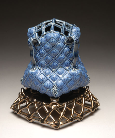 Margaret Bohls used a gridded plaster slab to make the lattice like texture on this pot. She then puffed out each square with her fingers to add volume.
