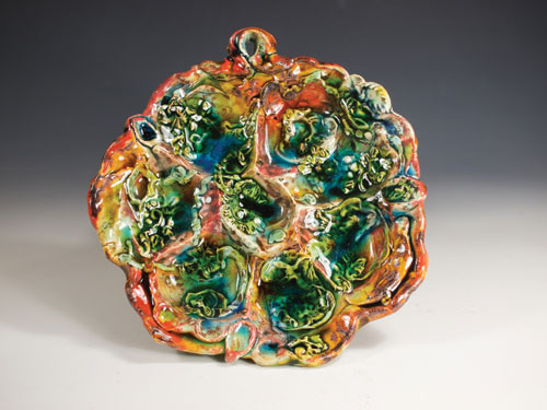 Oyster plate, 12 inches in diameter, earthenware with slips, sprigs and polychrome glazes, by Lisa Orr.