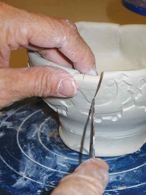 After the bowl form has dried to soft leather hard, the rim is marked in equal sections and darts are cut at those points.