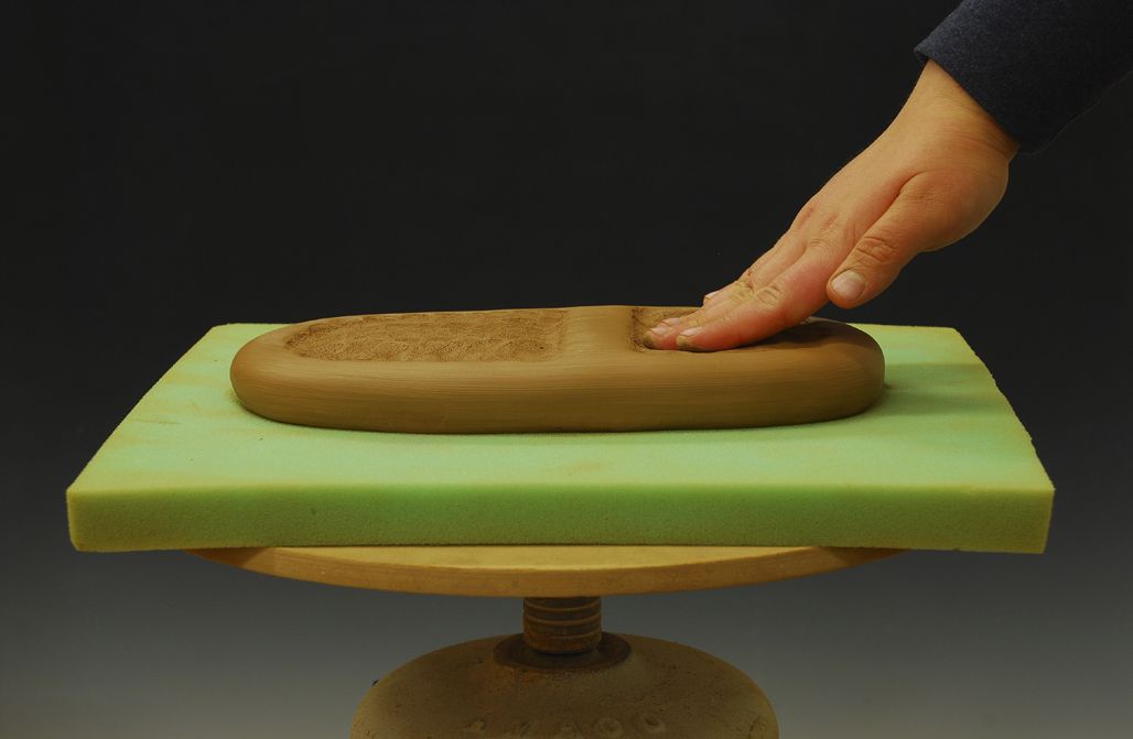 1. Initial stages of forming a vessel with her fingertips from a thick clay slab.