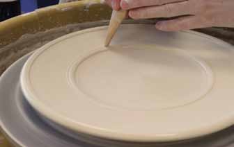 3 Use a rib to create a well in the center of the platter. Create defining lines around the well using a wooden knife.