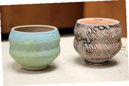 12 Two unfired teabowls with different slip patterns and underglaze painting techniques. The piece on the left has various brushed layers of underglaze. The piece on the right has stain added to the surface that is then wiped away.