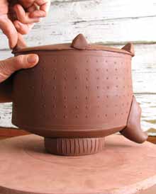 14 Flip the pot and add four pinched knobs for feet. Let them firm up.