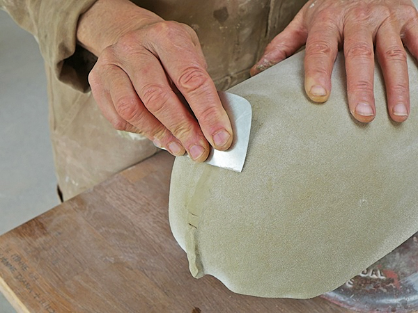 5. Smooth the join and compress the clay, pushing it against the mold with a rib.