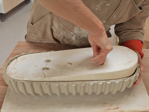 12. Loosen the edge of the rim slightly from the plaster to enable the mold to be lifted up and separated from the clay form.