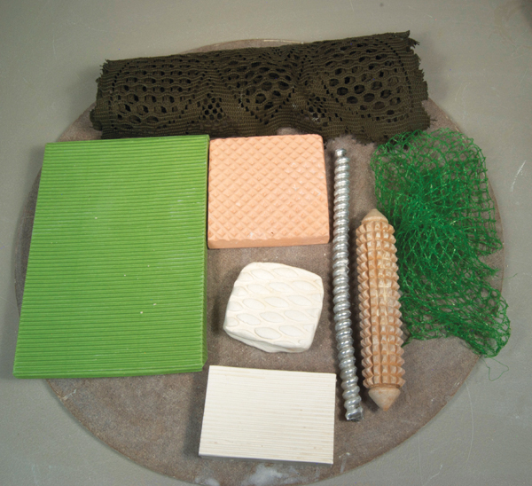 A variety of stamps and materials for embossing patterns onto clay slabs.