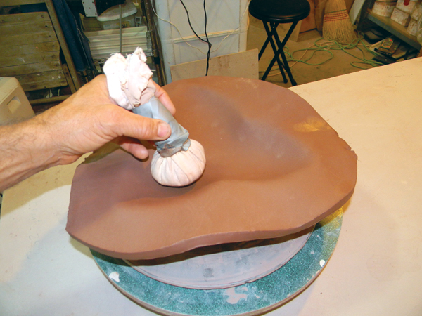 6. Fill a piece of fabric with sand, then lightly tap the slab to slump it into the mold.