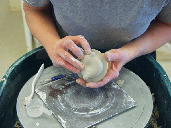 3 Carve out a notch on the rim of the lid between the added balls of clay for a drinking hole.