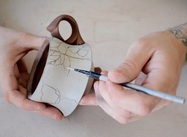 18 Carve patterns onto the mug, starting with a needle tool to create sgraffito lines. 