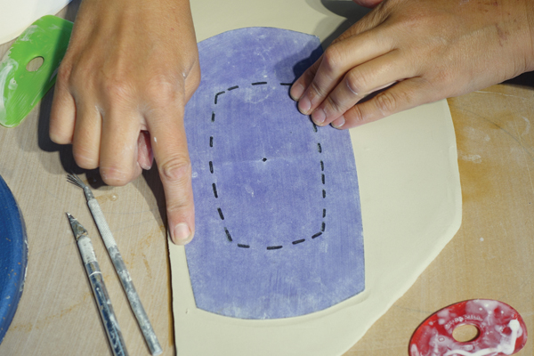 6 Using a template, press your finger down to mark the shape into a clay slab, then press on the center of each perforation mark.