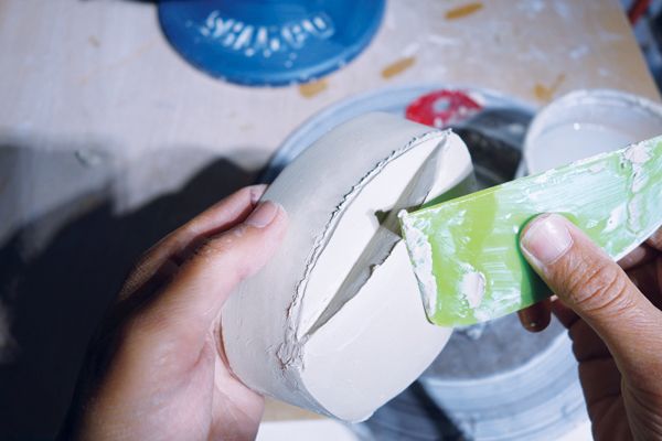 14 Attach the cat-eyed-shaped piece of clay to the leather-hard lid, add tiny coils to fill any gaps, then clean up the seams.