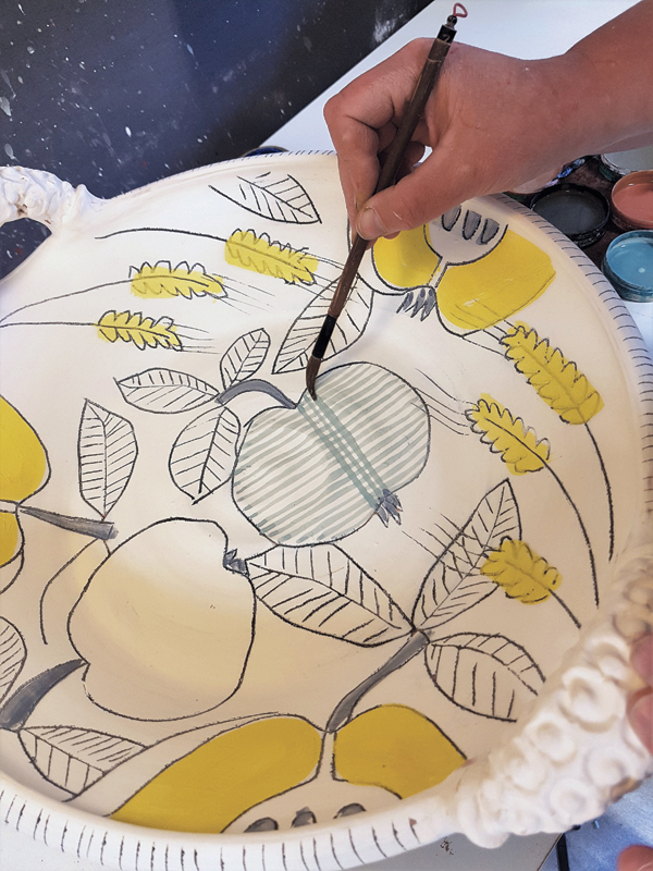 12 Add drawn designs using colored underglaze. Checkered apples are made with a fine liner brush.