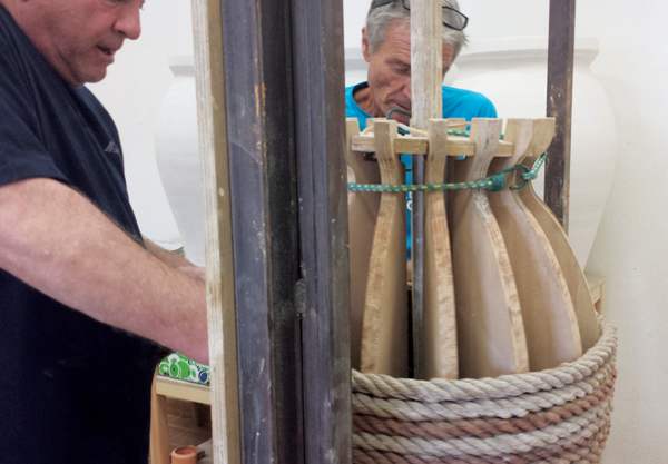 5 Coiling a thick rope around the wooden armature, starting at the slab base of the jar on the wheel head and working toward the top.