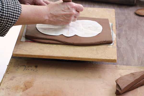 3 Place the paper template for the base on the two layered slabs. Use a knife to cut out the base with a slight angle.