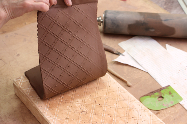 7 Roll slabs on the plaster tablet to transfer the pattern onto the clay. Use the slabs to build the wall and handle components.