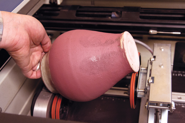 7 Jar being placed onto the rotary attachment in the laser etcher. 