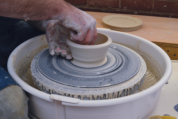 3 To shape a bowl with the chatter ribbing technique, first create a finger groove at the bottom of the exterior clay wall to prep the clay for a pull.