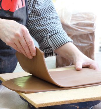 1 Roll out and layer two slabs for the raised platform base. Gently roll the two layers on a board covered with newsprint.