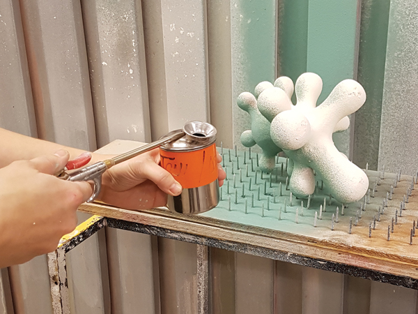 3 Applying slip to a sculpture on the bed-of-nails. I use an atomizer alongside a standard nozzle and air compressor to achieve the desired textured slip application.