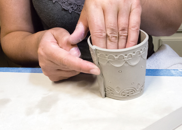 6 Form the body of the cup around your hand, score and slip the overlapped seam, then indent the seam edge.