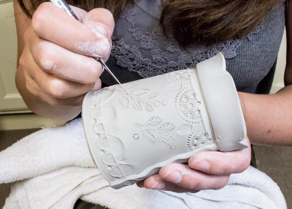 9 Use a craft knife to carve a branch and leaf design into the leather-hard clay. Use a light touch as the clay is very thin.