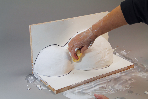 7 Smooth the plaster surface of your mold with a sponge and water as it starts to solidify