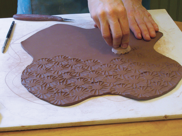 2 Add texture or a pattern to your slab by pressing a stamp into the clay surface.