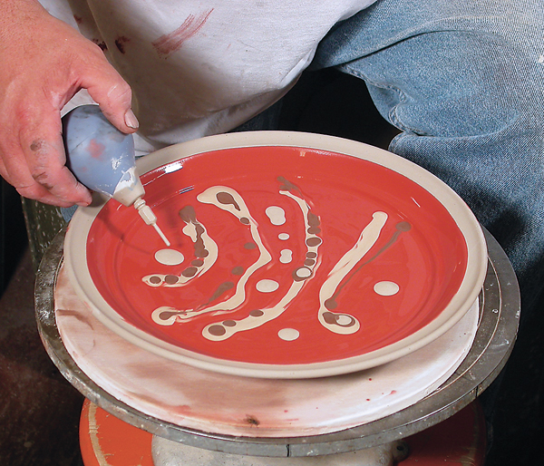 3 Preparing to marble by adding liquid slips over an iron-colored liquid slip.