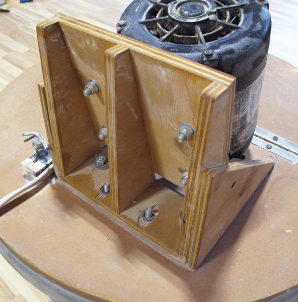 2 The square piece of wood that the motor is mounted to is attached to three triangular supports, which are attached to a rectangular base.