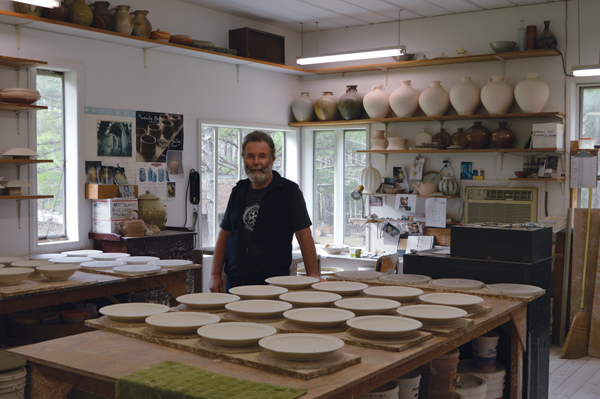 1 Geoff Pickett in the throwing room in his studio with dinnerware in production.