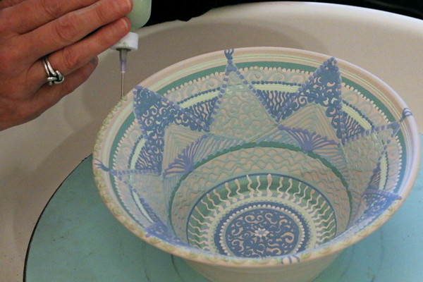 7 Add white dots, lines, and symbols to break up the cool colors, then apply water symbols on the rim.