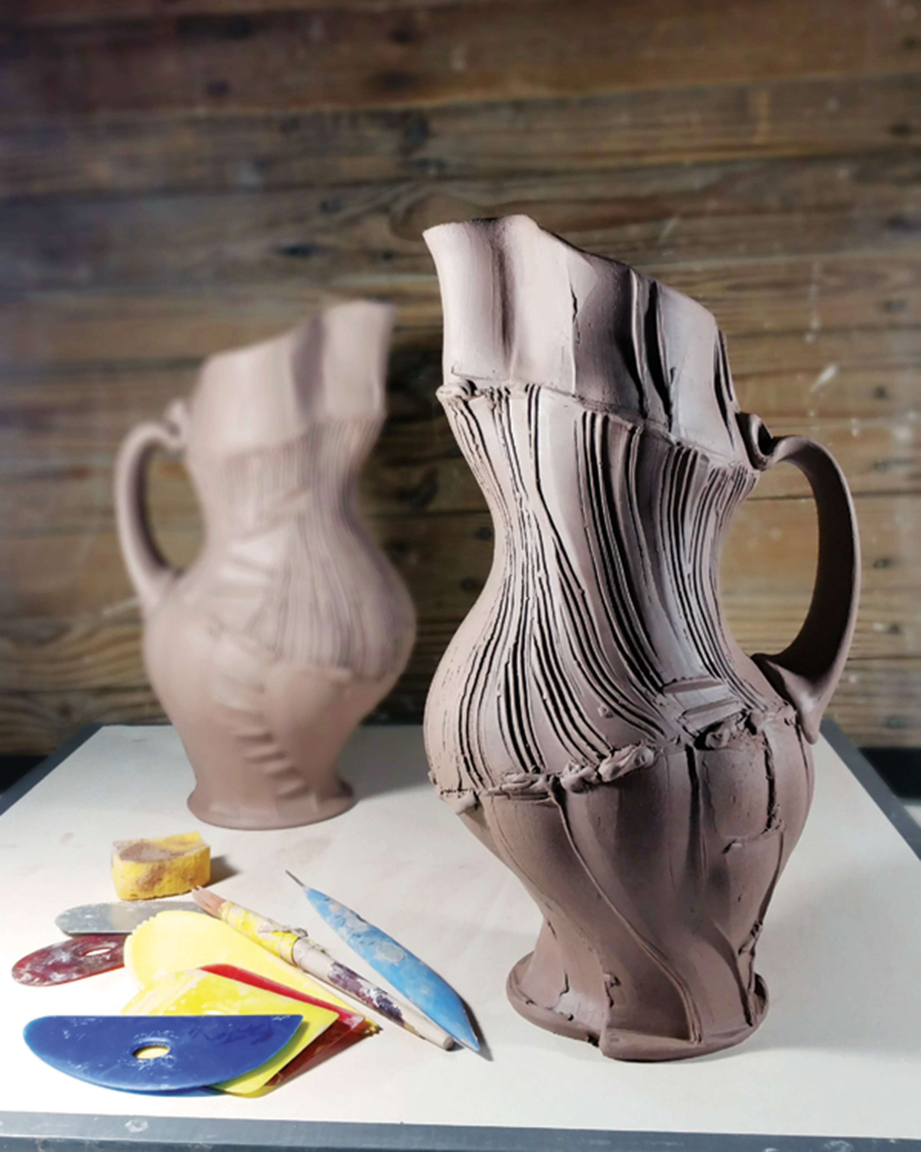 11 Two leather-hard pitchers, finished and drying, with an assortment of tools used to create them.