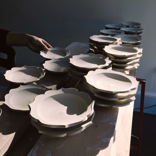 Hanako Nakazato stacking Chakra plates to finish drying after trimming them.