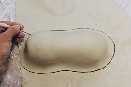 3 Stretch the slab over the Styrofoam balls to naturally form an oval shape. Cut the excess clay away.