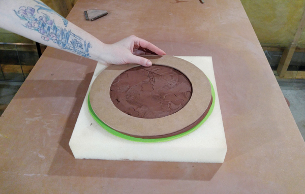 7 Registering the Masonite plate rim on the plate form, making sure it lines up with the edges of the clay.