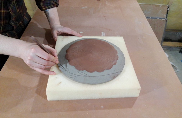 12 Using a knife tip to create drawings around the rim of the plate once the slip has begun to dry.