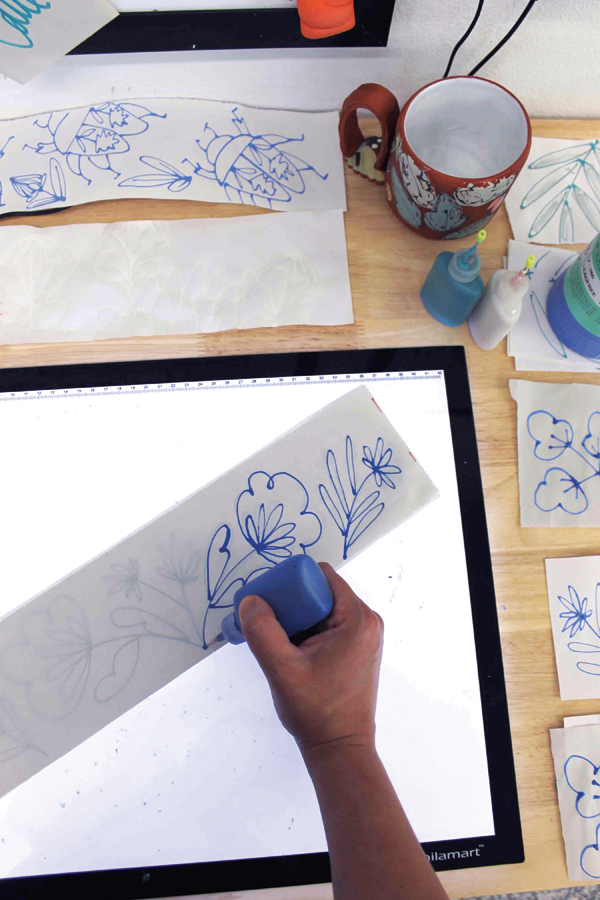2 Using a light tablet, place a sheet of newsprint over your template and trace the lines using underglaze in a slip trailer.